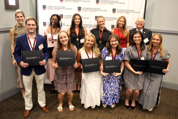 A group of students holding certificates pose for a picture in front of a step-and-repeat that says Cox Institute for Journalism, Innovation & Leadership, University of Georgia.
