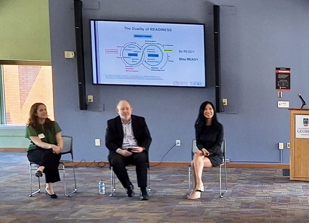 Three people sit in front of a digital sign with the headline The Duality of READINESS.