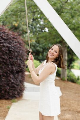 A young woman poses with the handle of a bell.