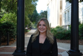 Danielle Zeitlin smiles in a headshot in front of the UGA Arch.