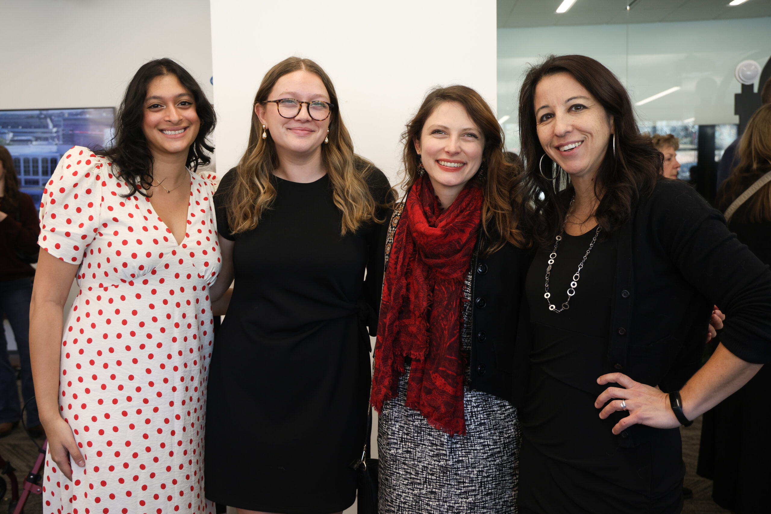 Four women poses for a picture in a room.