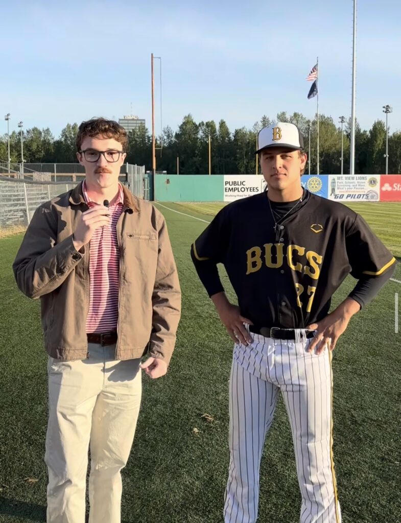 Ren Grimsley stands on a baseball field next to an Anchorage Bucs player for a postgame interview.