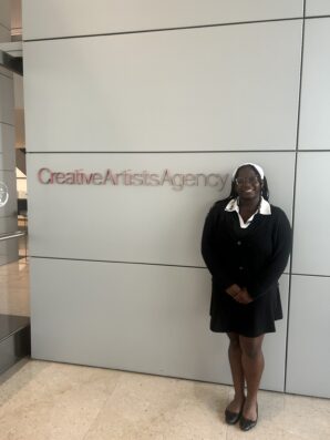 Ariel Greenway stands in front of a wall with the words Creative Artists Agency on the wall.