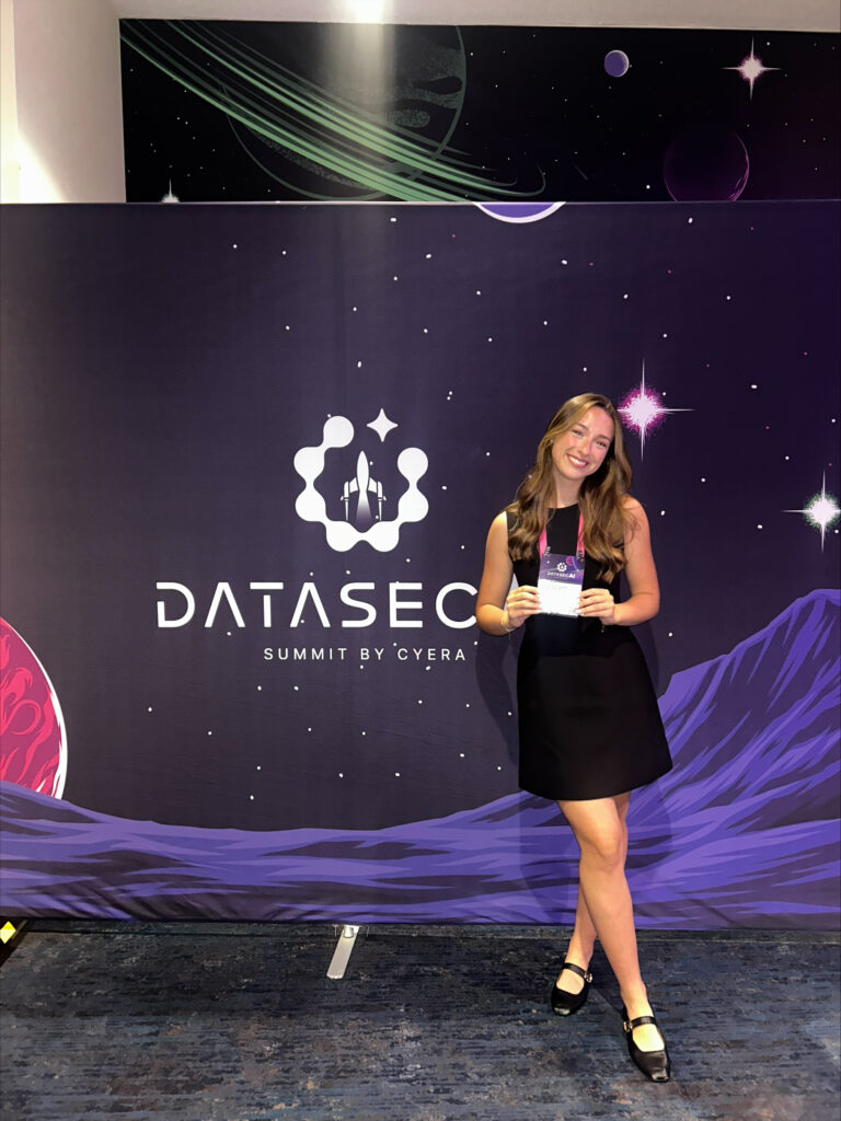 Elizabeth Nark stands in front of a backdrop for the conference she helped plan for Cyera.