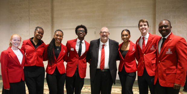 Dean Davis and a group of Ambassadors in red blazers pose for a picture.