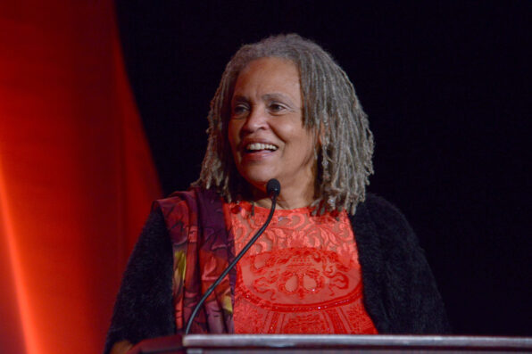 An older woman stands on stage in front of a microphone and podium.