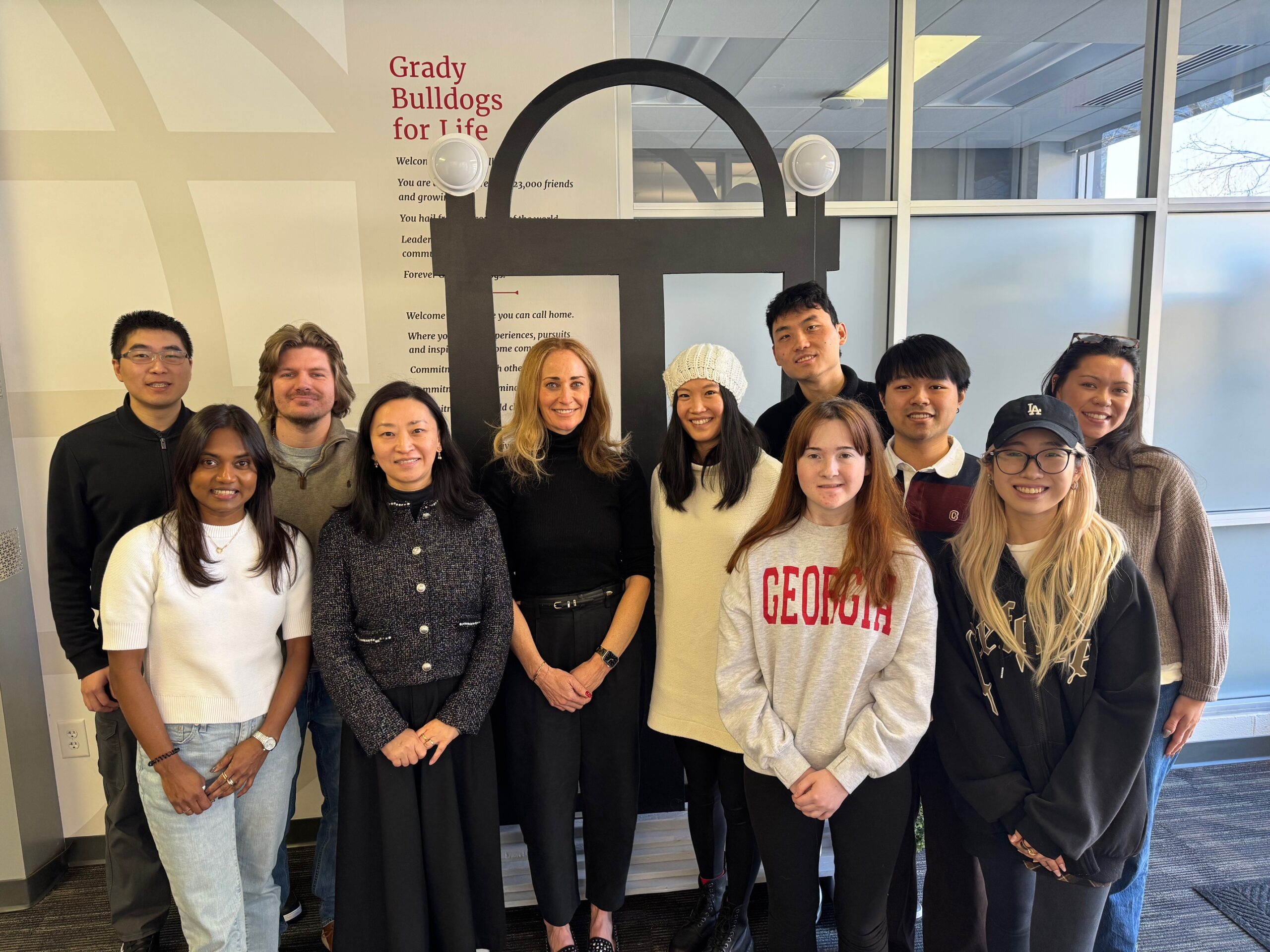 A group of students and faculty pose for a picture with a replica of the UGA Arch in the background.