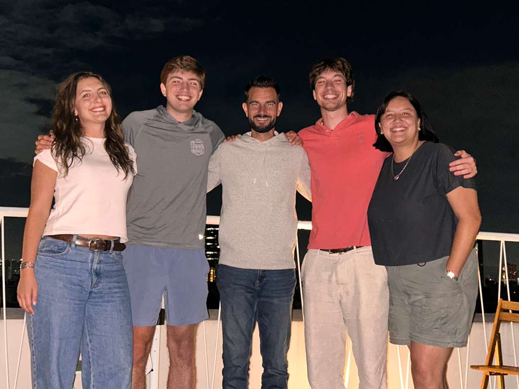 A nighttime picture of a group of students and their professor on a balcony.
