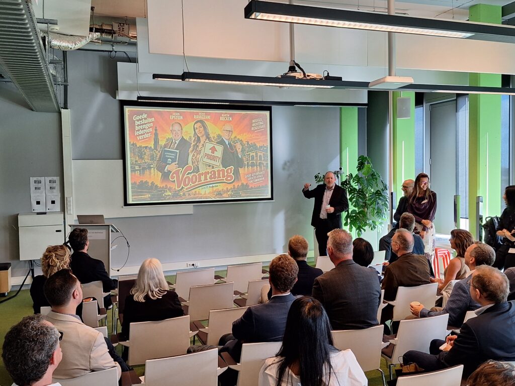 A man makes a gesture while talking with a group. On the digital screen is an AI image with exaggerated graphics.