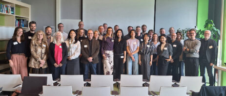 A large group of people pose for a picture in a meeting room.