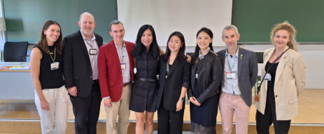 A group of 8 people pose for a picture in a classroom.