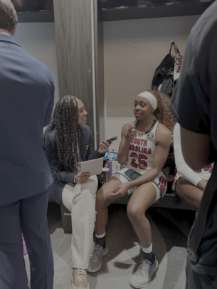 Alyssia Hamilton sits with a small microphone and interviews Raven Johnson, who wears a University of South Carolina basketball uniform.