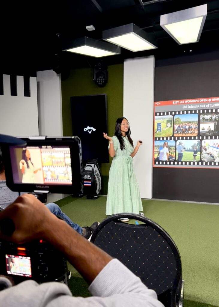 Anna La stands behind a camera giving a presentation at Callaway Golf Headquarters.