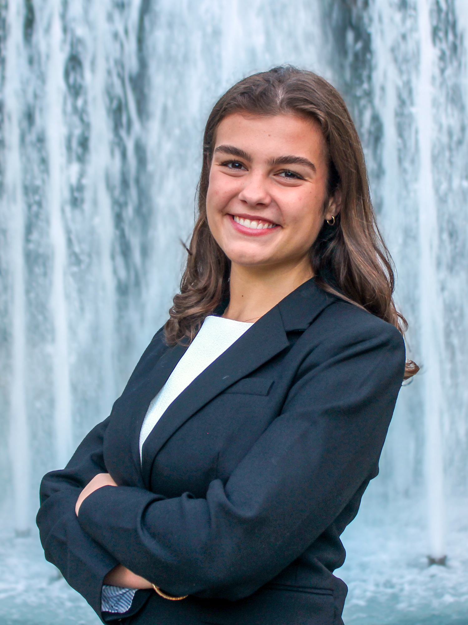 Outdoor headshot of Lizzie Hart with a fountain in the background.