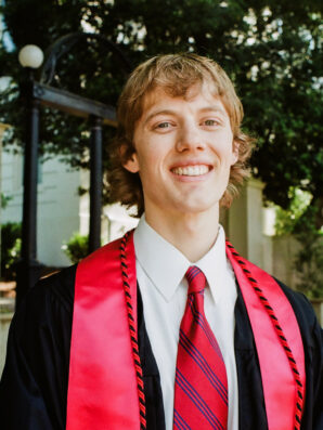 Outdoor headshot of Wyatt Stark in graduation gown and stole in front of UGA Arch