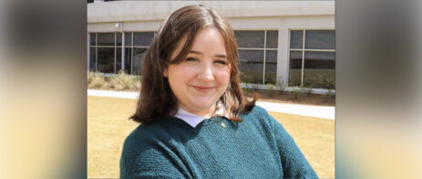 Marley Hinrichs stands in front of the Journalism Building for a headshot.