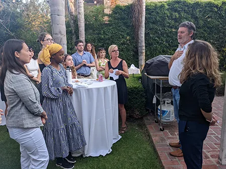 Jace Cook and Rachel O'Connor talk with students outside. A grove of palm trees is in the background.
