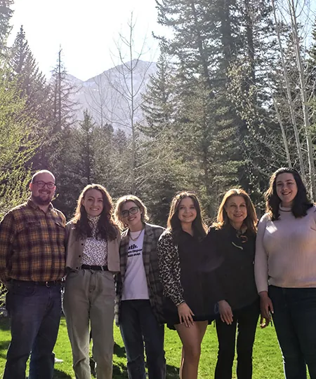Four students and two faculty pose for a picture in Utah in front of a grove of trees with a mountain in the background.