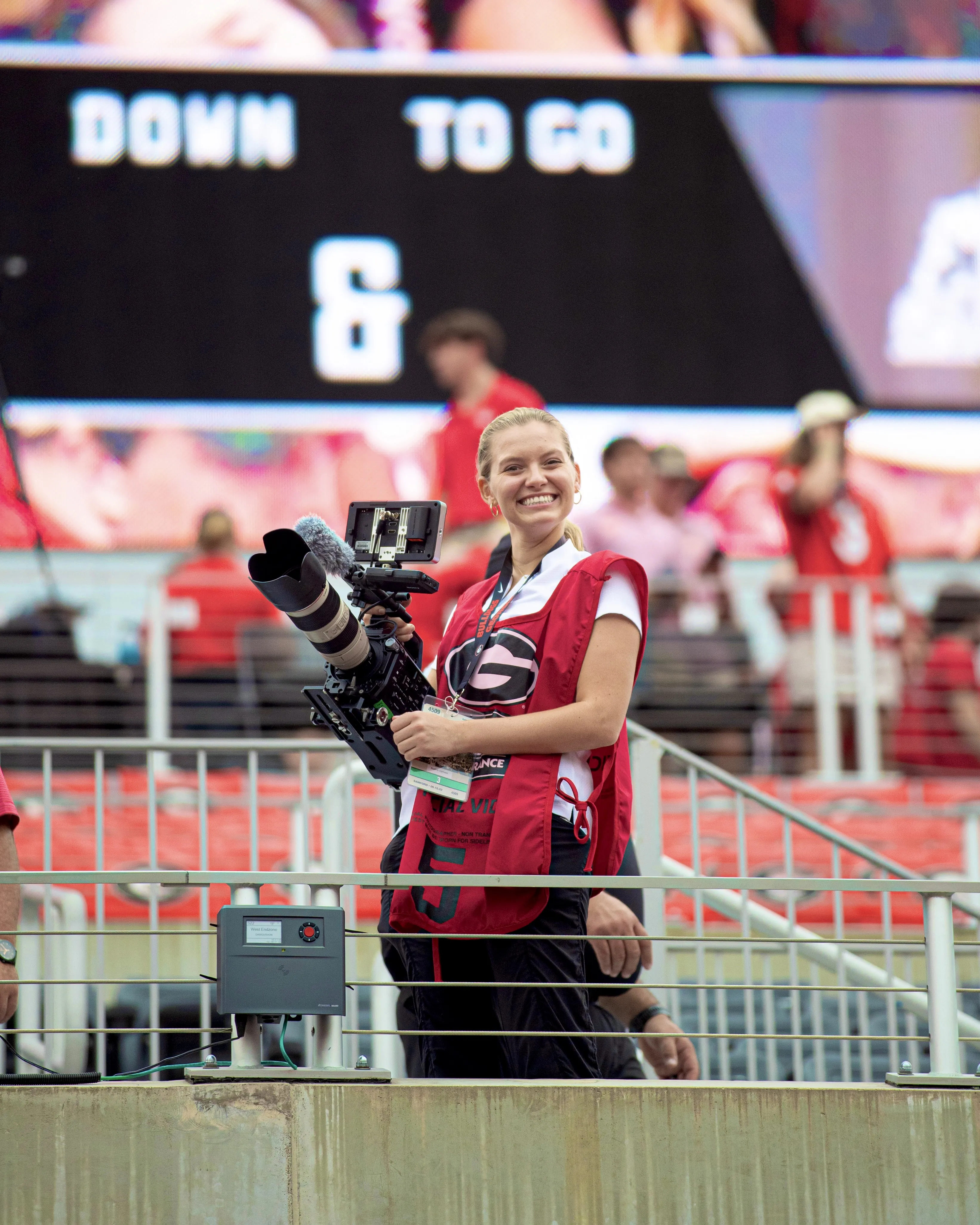 student holding a video camera smiling for a photo.