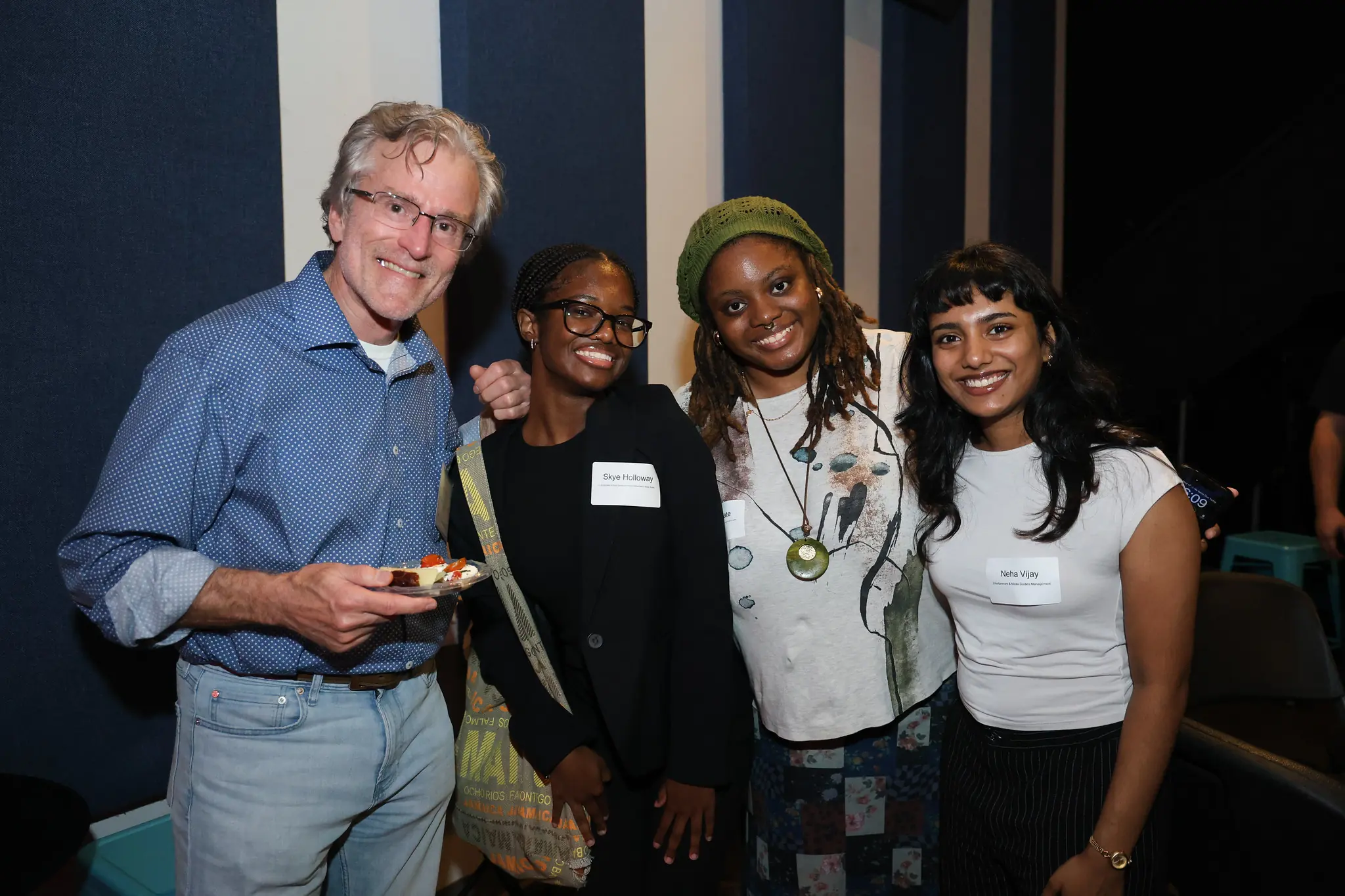 A professor and three female students pose for a picture at a networking event.