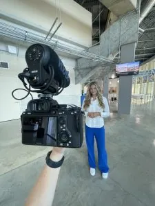 Photo of a person standing in front of a DSLR camera