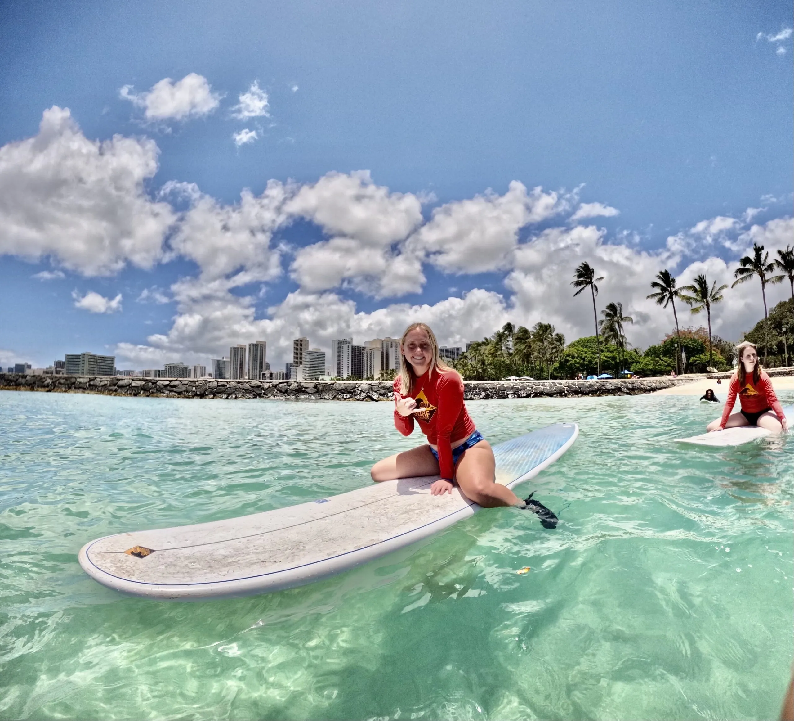 Anna Sergi, student on the Travel Writing in Hawaii study Away program 2024 sitting on a surf board during a group surf boarding excursion!