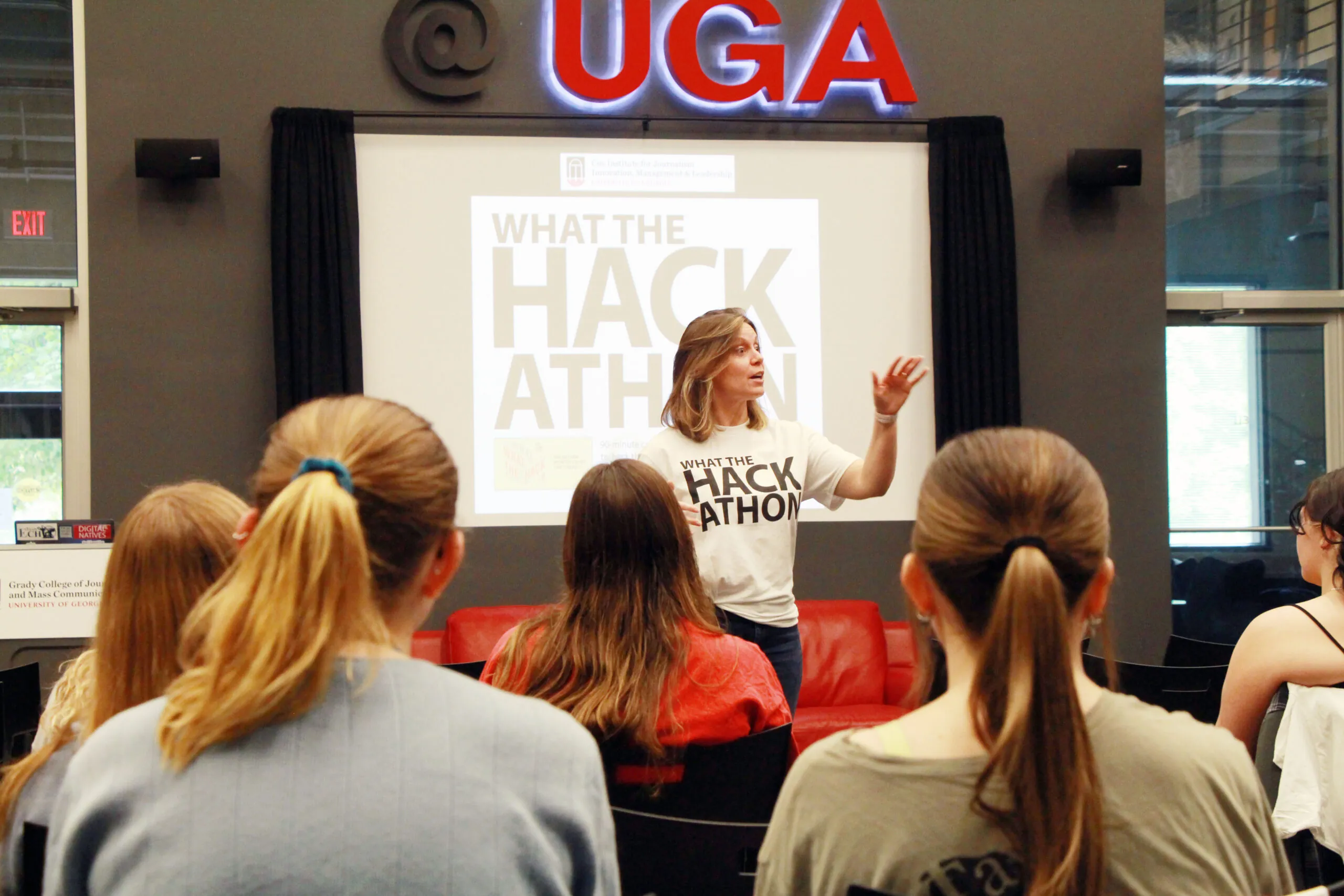 Amanda Bright stands in front of a screen that reads "What the Hackathon" to address students.