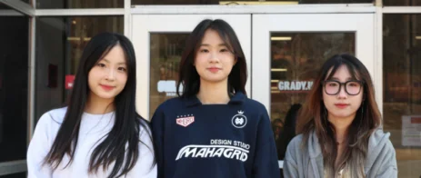 Students smile in front of Grady College.