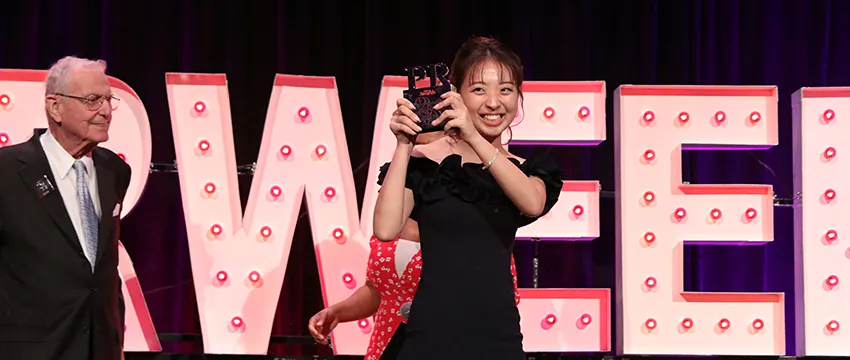 Esther Kim holds her trophy up as she crosses the stage.