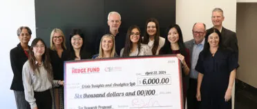 Students and industry professionals hold a large check