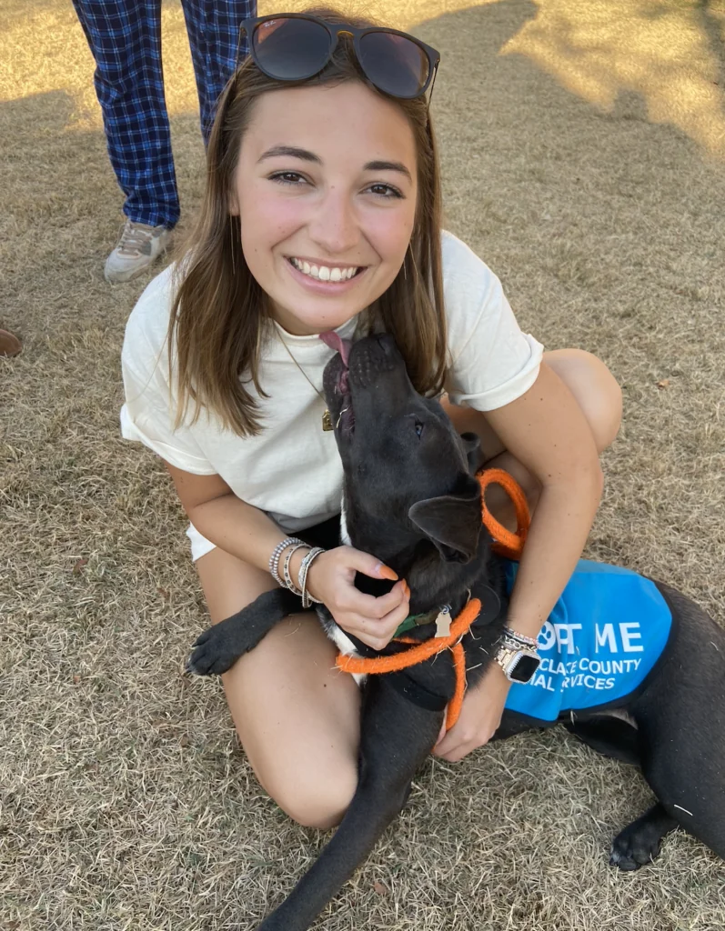A student poses with a puppy at a campus event