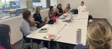 A group of Fink Fellow students sit in a round-table style discussion with Professor Lori Johnston in a Grady College room for their first meeting of the semester.
