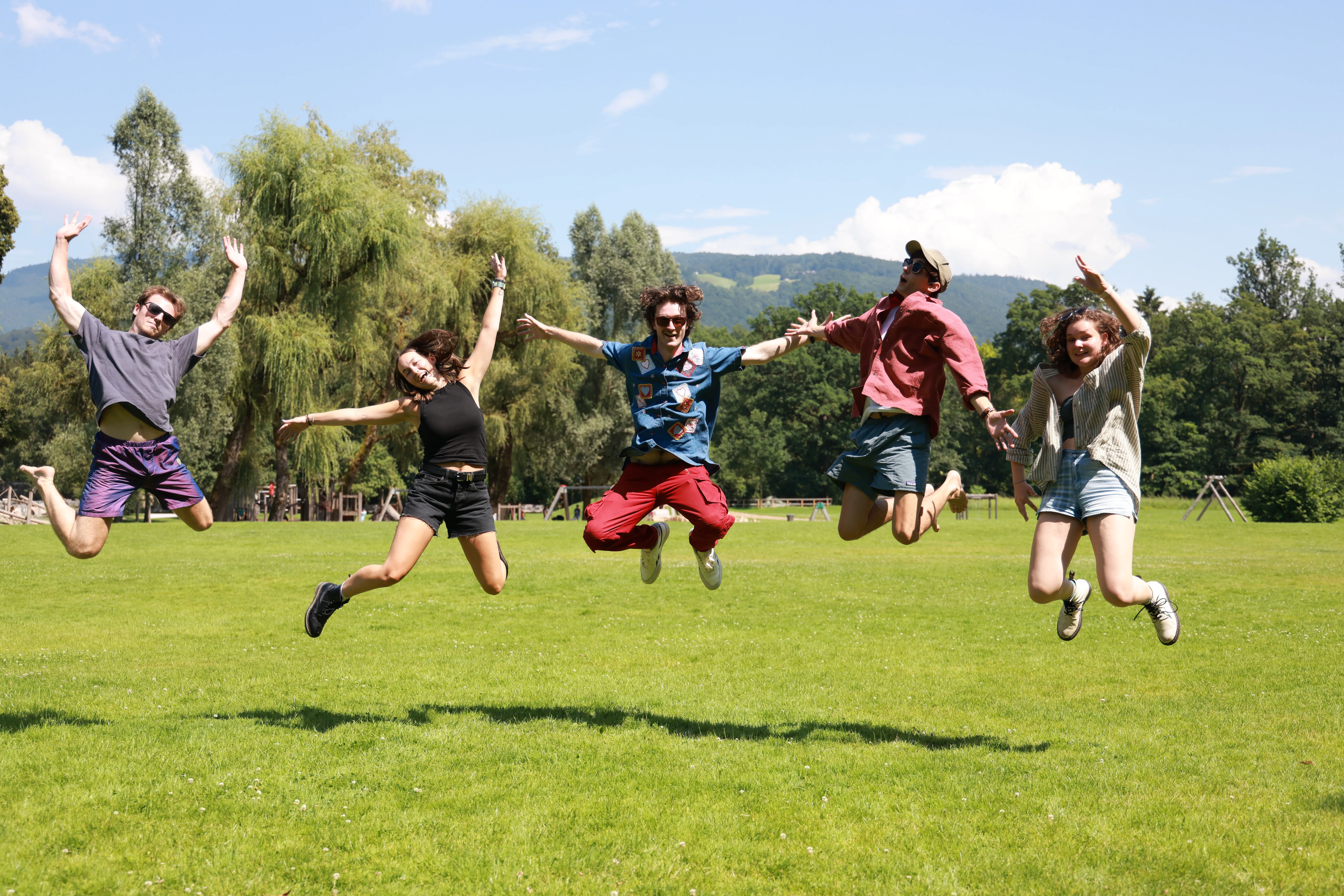 Students jumping in the air on a field of grass on the WWII Foundation Filmmaking Program 2024.