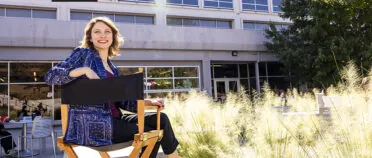 Lauren Musgrove sits in a director's chair outside Grady College.