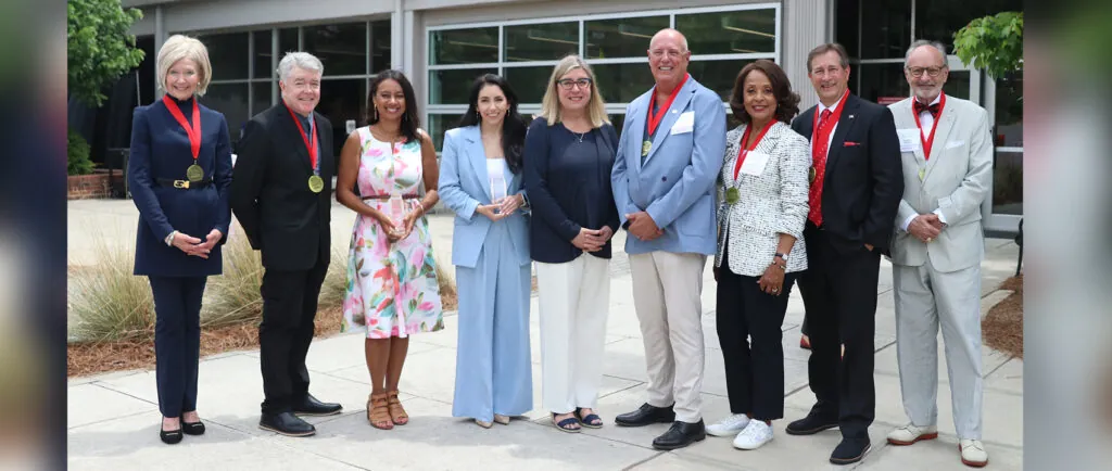 Salutes honorees wear their medals and hold awards in front of Grady College.