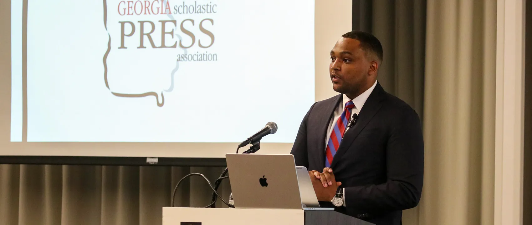 Willie Daniely speaks at a lectern in front of a screen with a GSPA logo.