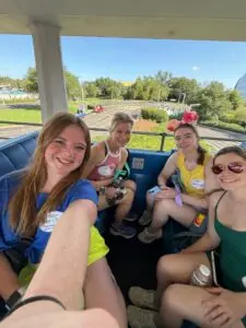 Four women ride on a Disney Peoplemover cart.