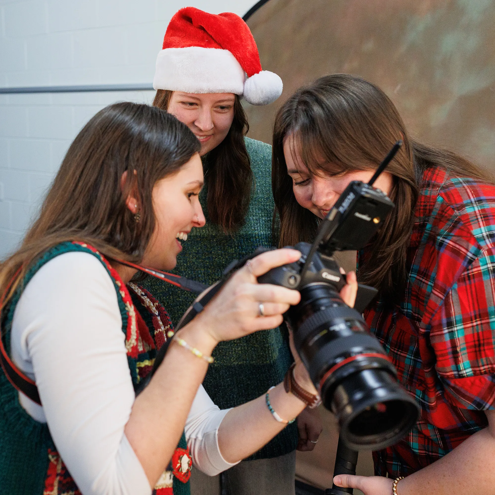 Students huddle around a camera to view a picture playback.