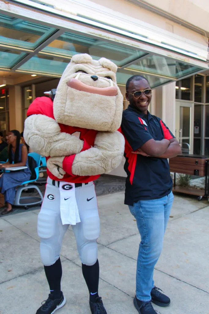 Hairy Dawg (left) poses with De'Ondre (right) in front of Grady College.