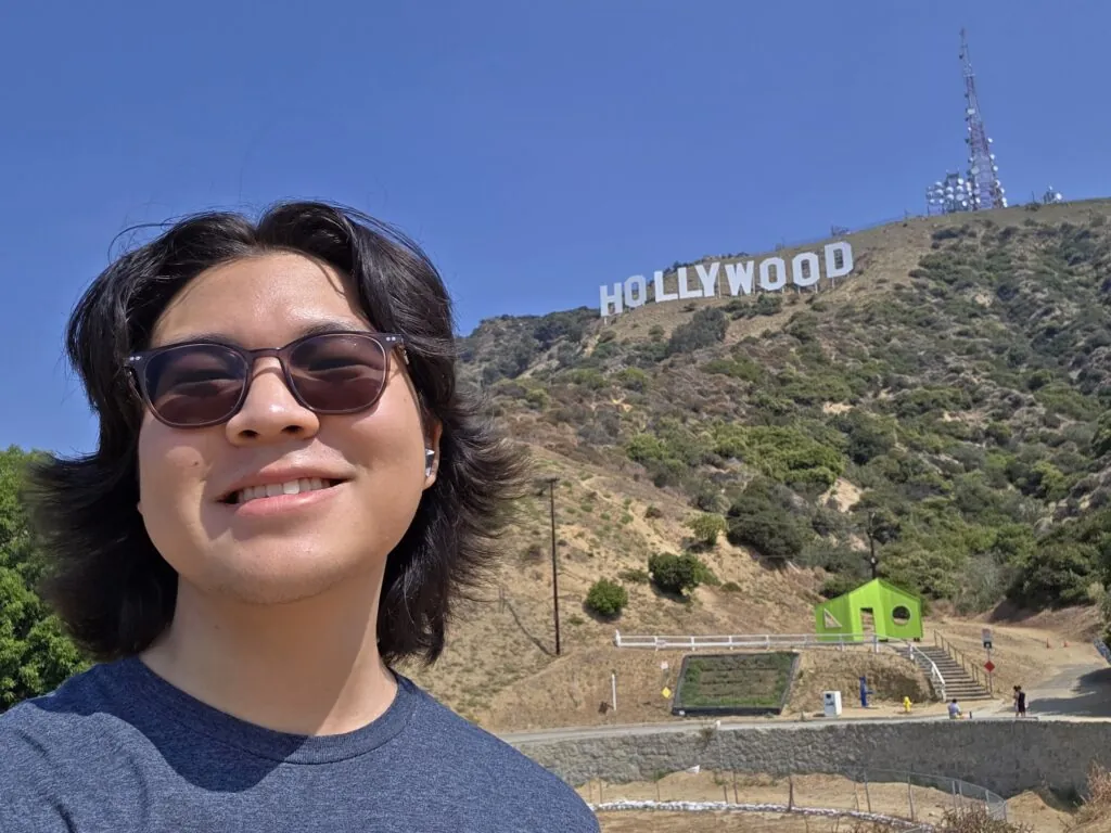 Justin smiles in a selfie in front of the Hollywood sign.