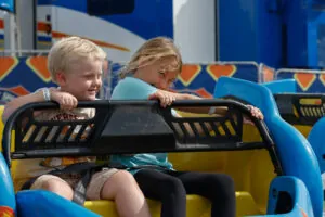 Two children smile as they enjoy a ride at the fair.