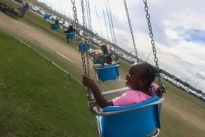 A profile view of a girl in a row of swings at the fair.