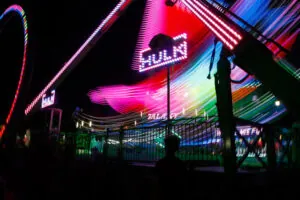 The blur of neon lights and a sign that reads "Hulk" at the fair.