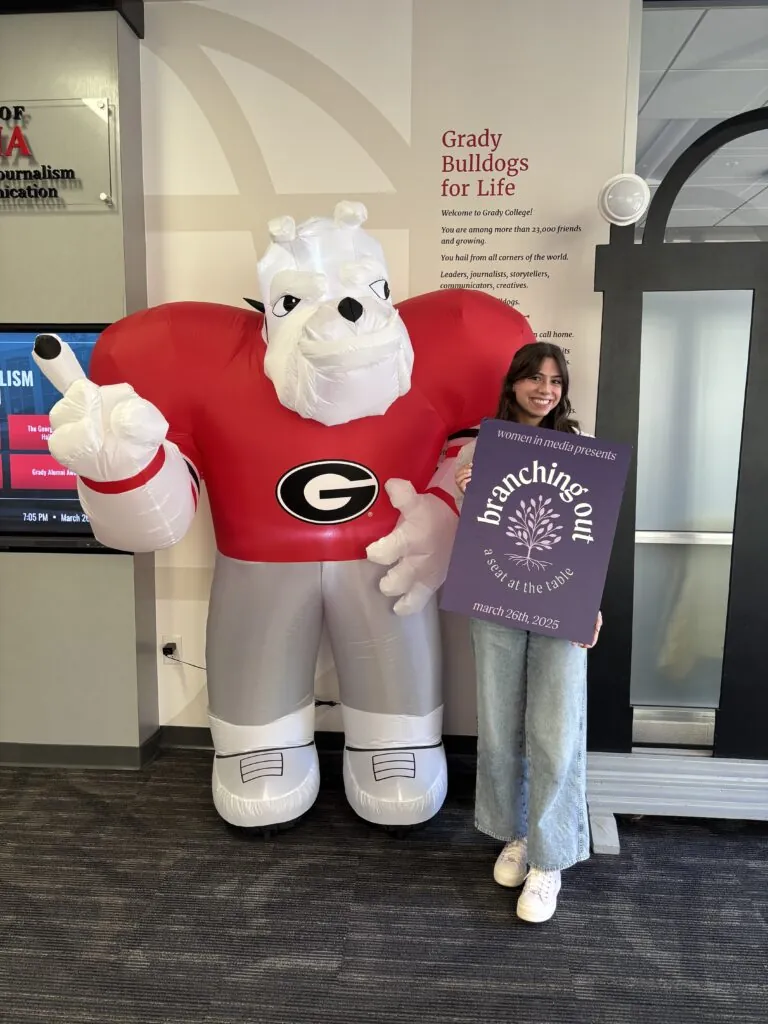 Ally poses in front of the Peyton Anderson Forum in Grady next to a blow-up version of Hairy Dawg,