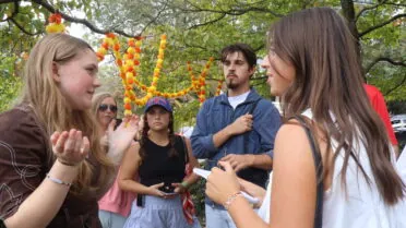 Students stand in a circle interviewing event participants.