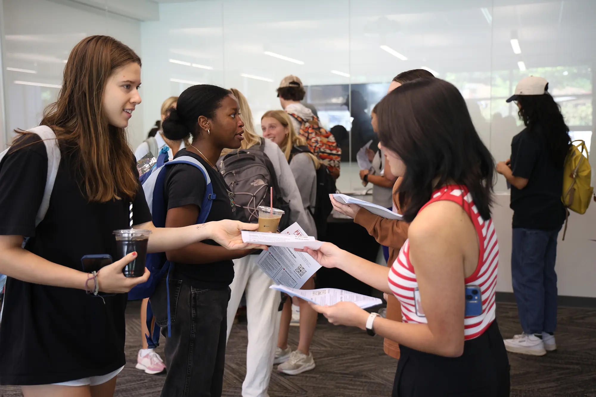 Student smiles as another student hands her a flyer.