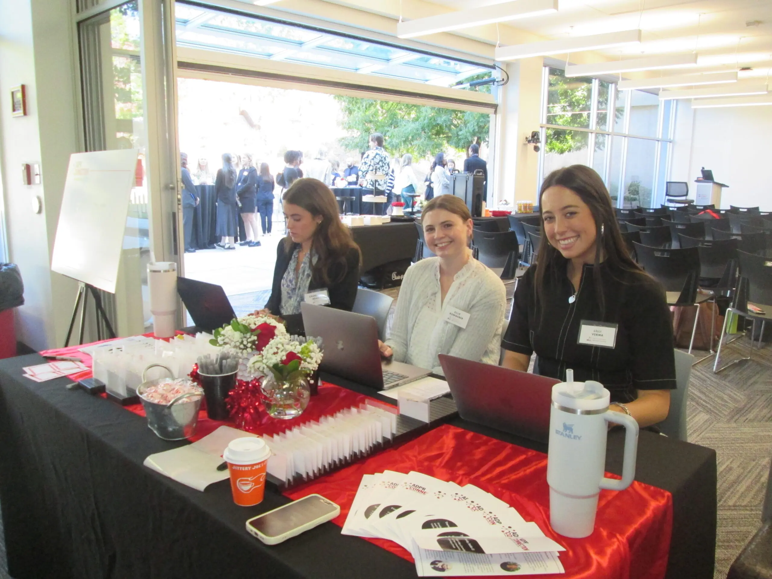 Lilli Verma sits with two other women at a reception table at ADPR Connection 2024.