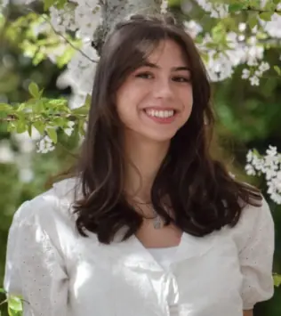 Headshot of Ally Kramer in front of flowering tree.