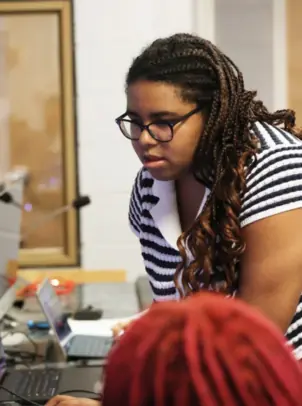 Profile of Sabrina Felix as she leans over tech board.