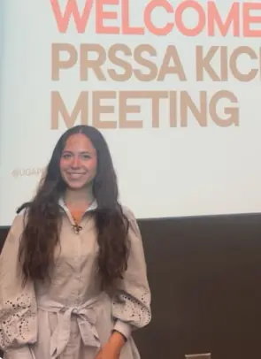 Picture of Sydney Brass in front of screen that reads Welcome to PRSSA Kick off Meeting